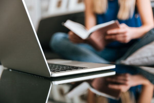 laptop table near woman reading book home thumb